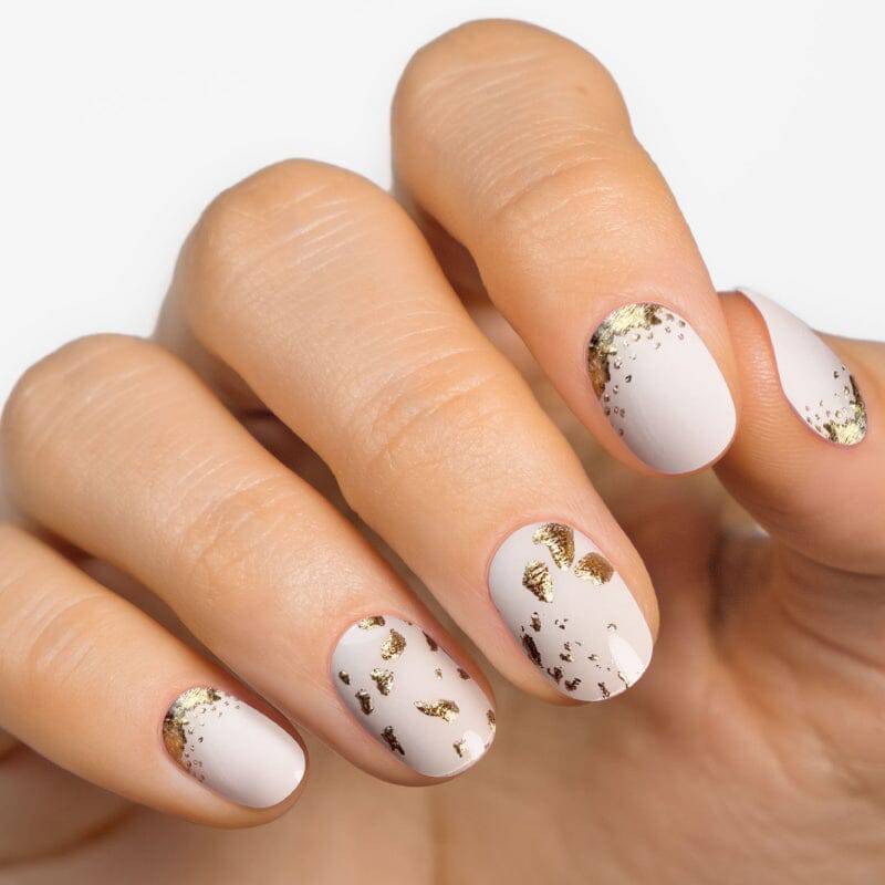 White cream nails with gold foil accents.