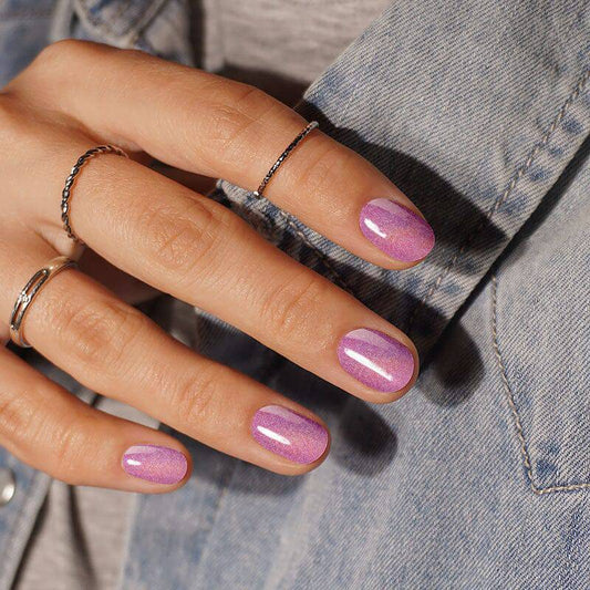 Hologrphic pink nails with an ombre effect, paired with a denim jacket for a trendy look.