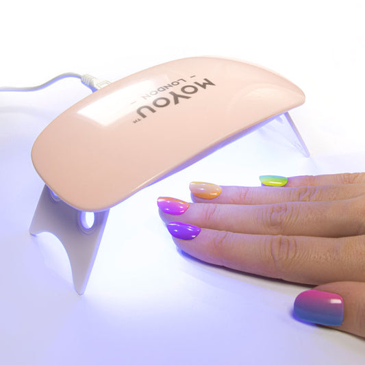 Colourful gel nail strips manicured being cured under UV/LED lamp
