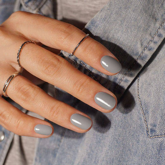 Chic gray manicure with a high-shine finish, complemented by a denim jacket backdrop.
