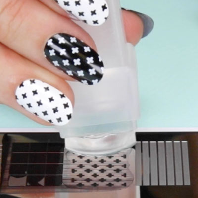 Nail art design being picked up from a nail stamping plate using a stamper